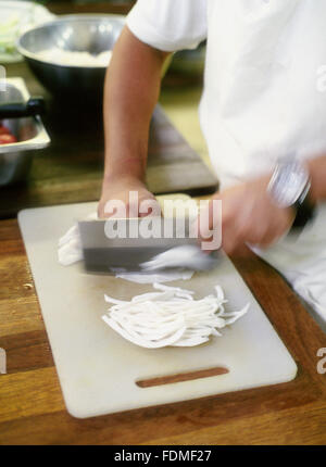 A kitchen helper cuts onions in the kitchen at The Farm at San Benito, Philippines. Stock Photo