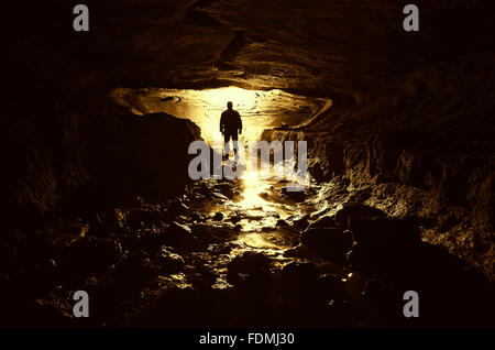 Silhouette of man exploring underground cave Stock Photo
