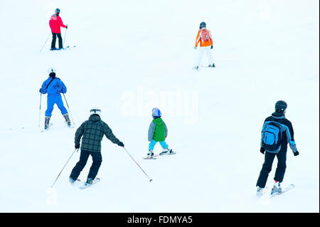 Group of a skiers on a mountain slope at ski resort. Back view Stock Photo