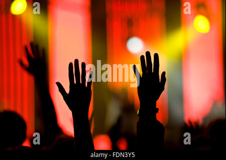 Worshipers raise their silhouetted hands against a colorful background during a religious conference Stock Photo