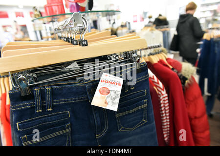 Clothes displayed in a charity shop UK  hanging on coat hangers. Stock Photo