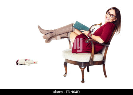 Studio shot of attractive woman relaxes with a book in an armchair. Stock Photo