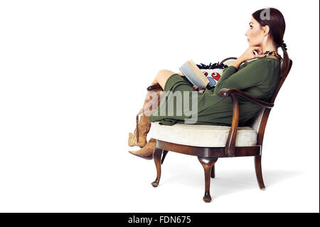 Studio shot of pensive woman sitting comfortably in a armchair. Stock Photo