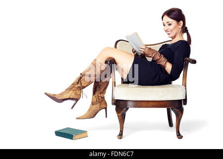 Attractive woman reading a book while sitting comfortably in an old chair. Stock Photo