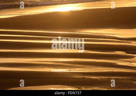 Sunset and ripple patterns on the sand at Bournemouth, UK, beach Stock Photo