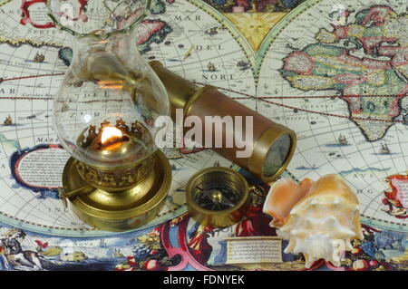 Vintage spyglass, compass, seashell and kerosene lamp lie on an old map of the world. Stock Photo