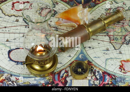 Compass, old telescope, kerosene lamp and seashell lying on an old map of the world. Stock Photo