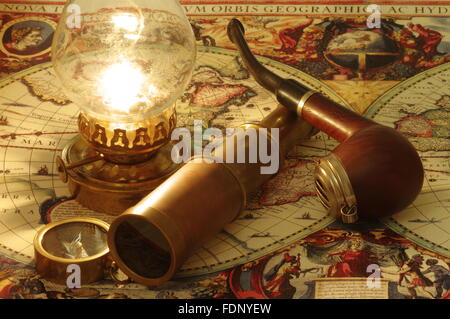 Old lunette, pipe, compass and kerosene lamp lying on the vintage map of the world. Stock Photo