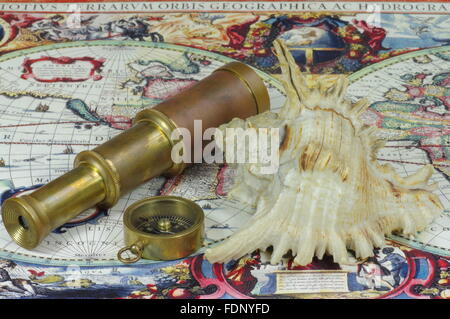 Vintage telescope, compass and shell lie on the old map of the world. Stock Photo