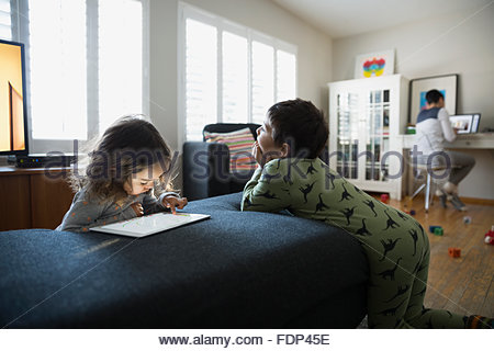Brother and sister using digital tablet living room