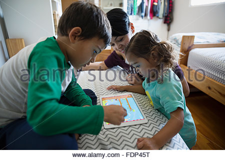 Mother and children playing game on digital tablet