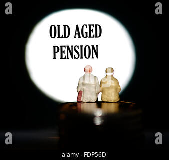 Miniature figurine pensioners sitting on coins in front of a spotlight showing the words Old age pension concept Stock Photo