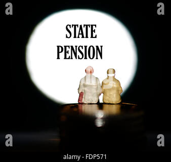 Miniature figurine pensioners sitting on coins in front of a spotlight showing the words State pension concept Stock Photo