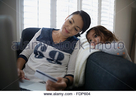 Daughter watching mother with laptop online shopping