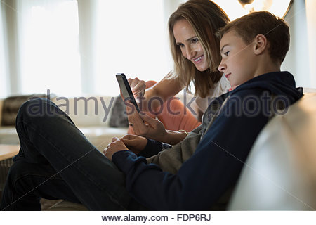 Mother and son using cell phone on sofa