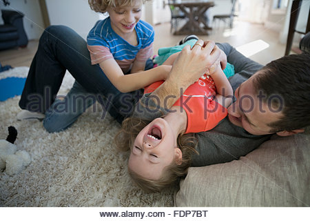 Father And Brother Tickling Sister On Rug Stock Photo Father And Brother Tickling Sister On Rug Stock Photo