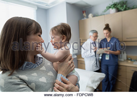 Mother holding baby in pediatrician examination room Mother holding baby in pediatrician examination room