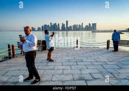 Tourists Taking Photographs With The Skyscrapers Of West Bay In The Backround, Doha, Qatar Stock Photo