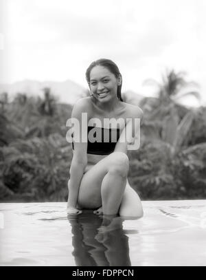 A woman sits on the ledge of the infinity pool at The Farm at San Benito, Philippines. Stock Photo