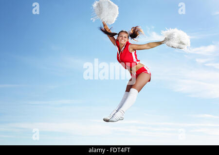 Young beautiful female cheerleader in uniform jumping high Stock Photo