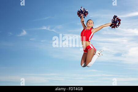 Young beautiful female cheerleader in uniform jumping high Stock Photo