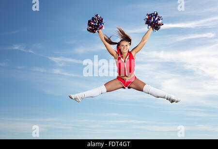 Young beautiful female cheerleader in uniform jumping high Stock Photo