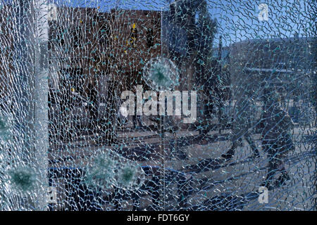 Pedestrians are seen through a reinforced glass window which was riddled with bullet holes in the central bus station West Jerusalem Israel Stock Photo