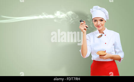 Young female chef in red apron against collour background Stock Photo