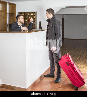 The receptionist and a client discuss at the hostel reception desk. Stock Photo