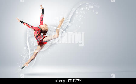 Young cute woman in gymnast suit show athletic skill on white background Stock Photo