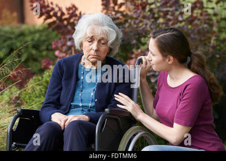 Adult Daughter Comforting Senior Mother In Wheelchair Stock Photo