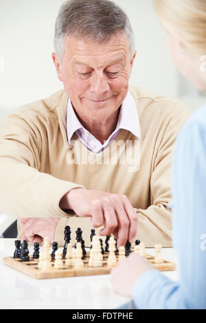 Senior Man Playing Chess With Teenage Granddaughter Stock Photo