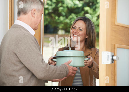 Woman Bringing Meal For Elderly Neighbour Stock Photo