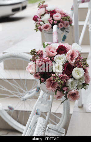 Creative bouquet of colorful artificial flowers on old white bicycle. Selective focus and space in the zone blurring composition Stock Photo