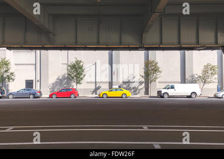 Cars parked on the street under overpass in Manhattan, NYC. Stock Photo