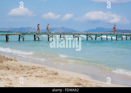 Beach with emerald crystal clear water and people on the jetty on a sunny summer morning in July Stock Photo