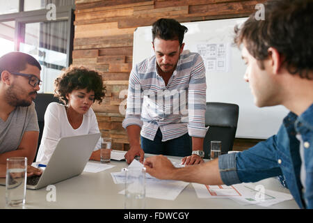 Young man discussing market research with colleagues in a meeting. Team of young professionals having a meeting in conference ro Stock Photo