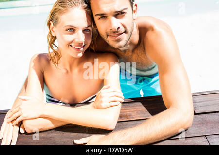 Happy couple leaning on pool edge Stock Photo