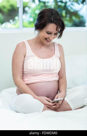 Pregnant woman using her smartphone Stock Photo