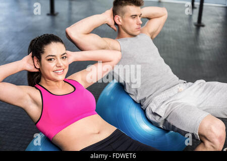 Fit couple doing abdominal crunches on fitness ball Stock Photo