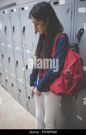 Sad student leaning on locker Stock Photo