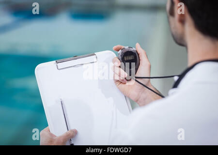 Handsome trainer holding stopwatch and reading clipboard Stock Photo