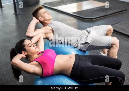 Fit couple doing abdominal crunches on fitness ball Stock Photo