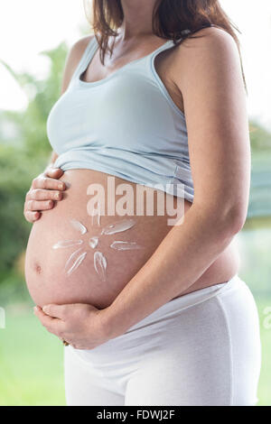 Pregnant woman applying cream on her belly Stock Photo
