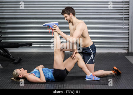 Male trainer assisting woman stretching Stock Photo