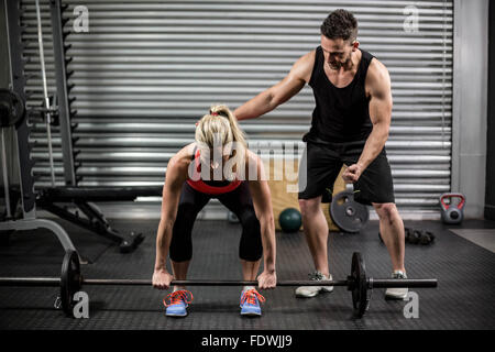 Trainer helping woman with lifting barbell Stock Photo