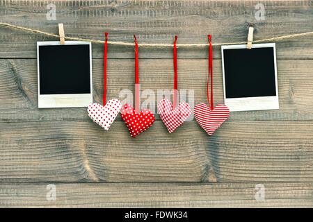 Red hearts and blank vintage polaroid photo frame hanging on the clothesline. Handmade Valentines Day decoration Stock Photo