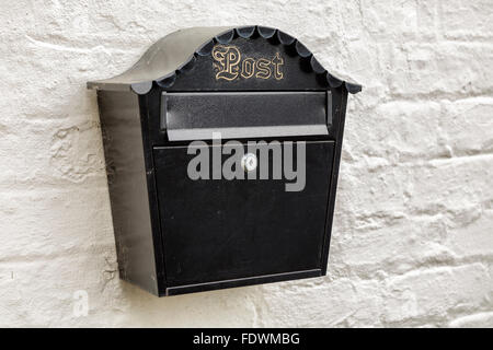 Black mailbox with gold lettering on a white brick wall  Model Release: No.  Property Release: No. Stock Photo