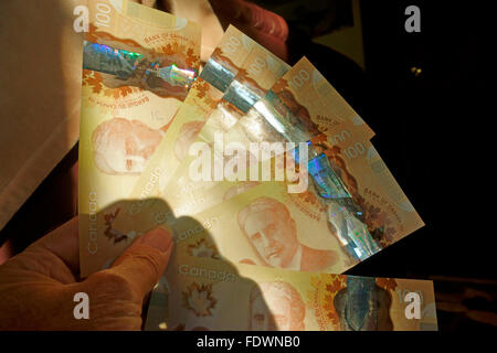 Canadian 100 one hundred dollar bills paper money held in a hand Stock Photo