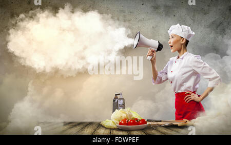 Asian female cook screaming loud in megaphone Stock Photo